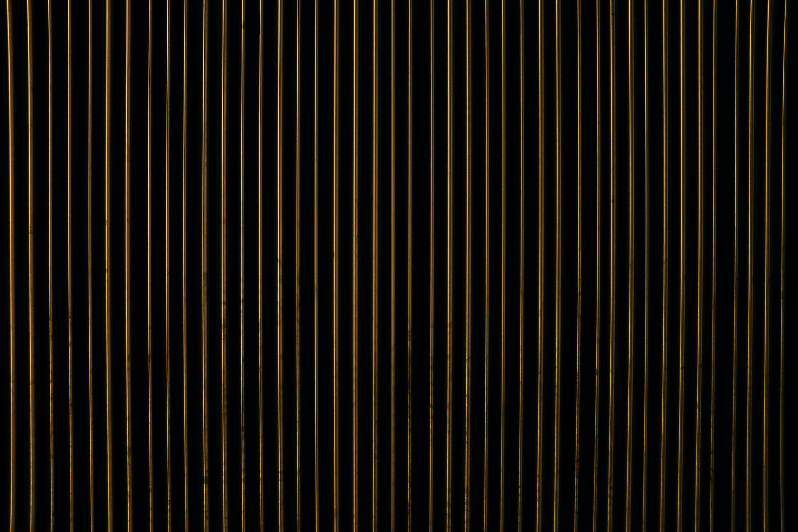 Aajkitajikhabar .com A close-up view of an abstract pattern with vertical gold and black stripes, creating a textured design.