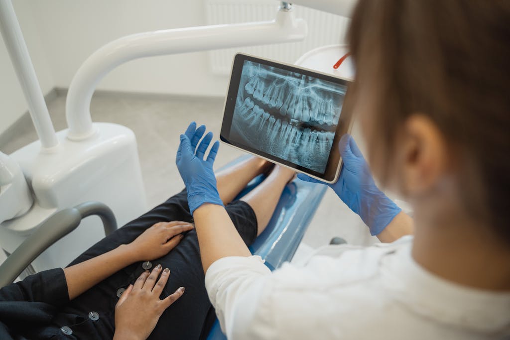 Dental Software News Today A dentist showing a dental x-ray on a tablet to a patient in a clinic.