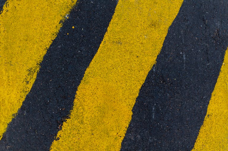 Mansutfer A high-angle close-up of yellow and black road markings on asphalt surface.