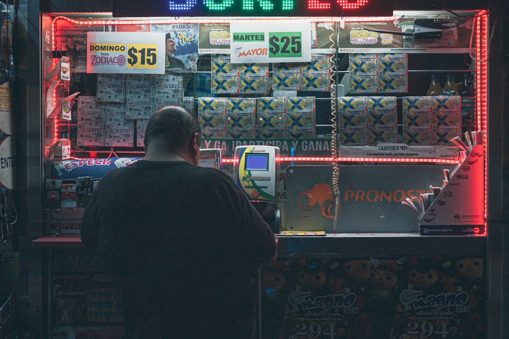 Florida Woman Wins Monopoly Lottery A man purchasing a lottery ticket at an illuminated kiosk in Mexico City, highlighting risk and hope.