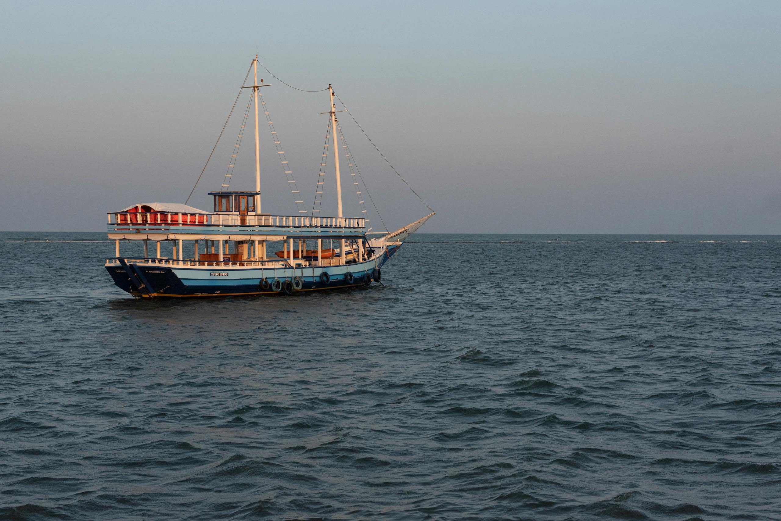 juntos seguros A serene sailing boat glides on the ocean at sunset near Porto Seguro, Brazil.