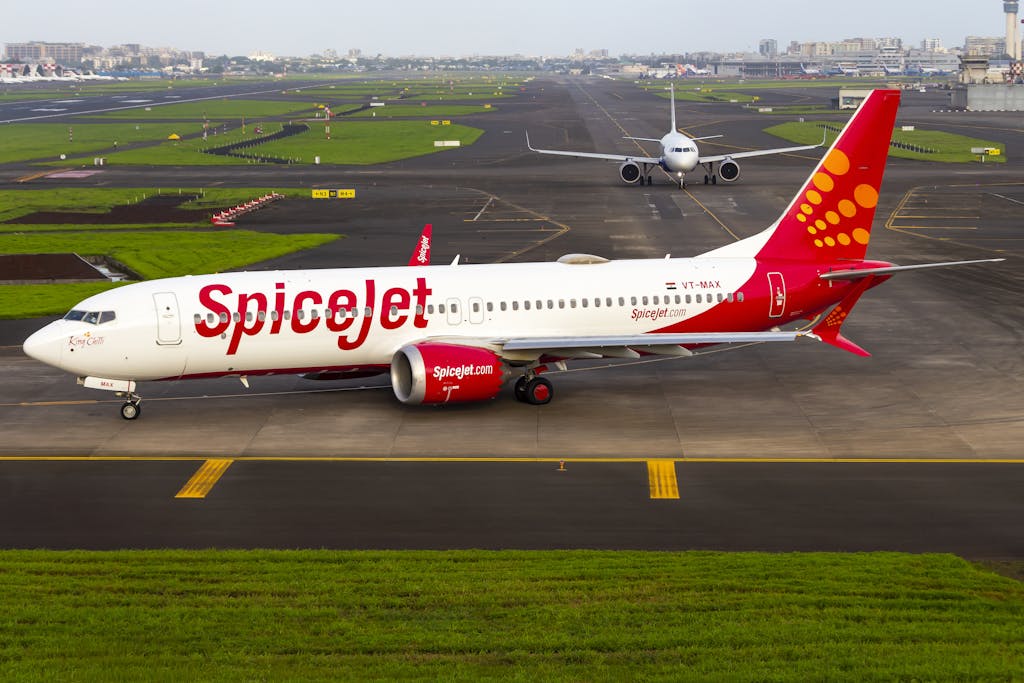 ibomma1.com A SpiceJet airplane waits on a bustling runway ready for takeoff.
