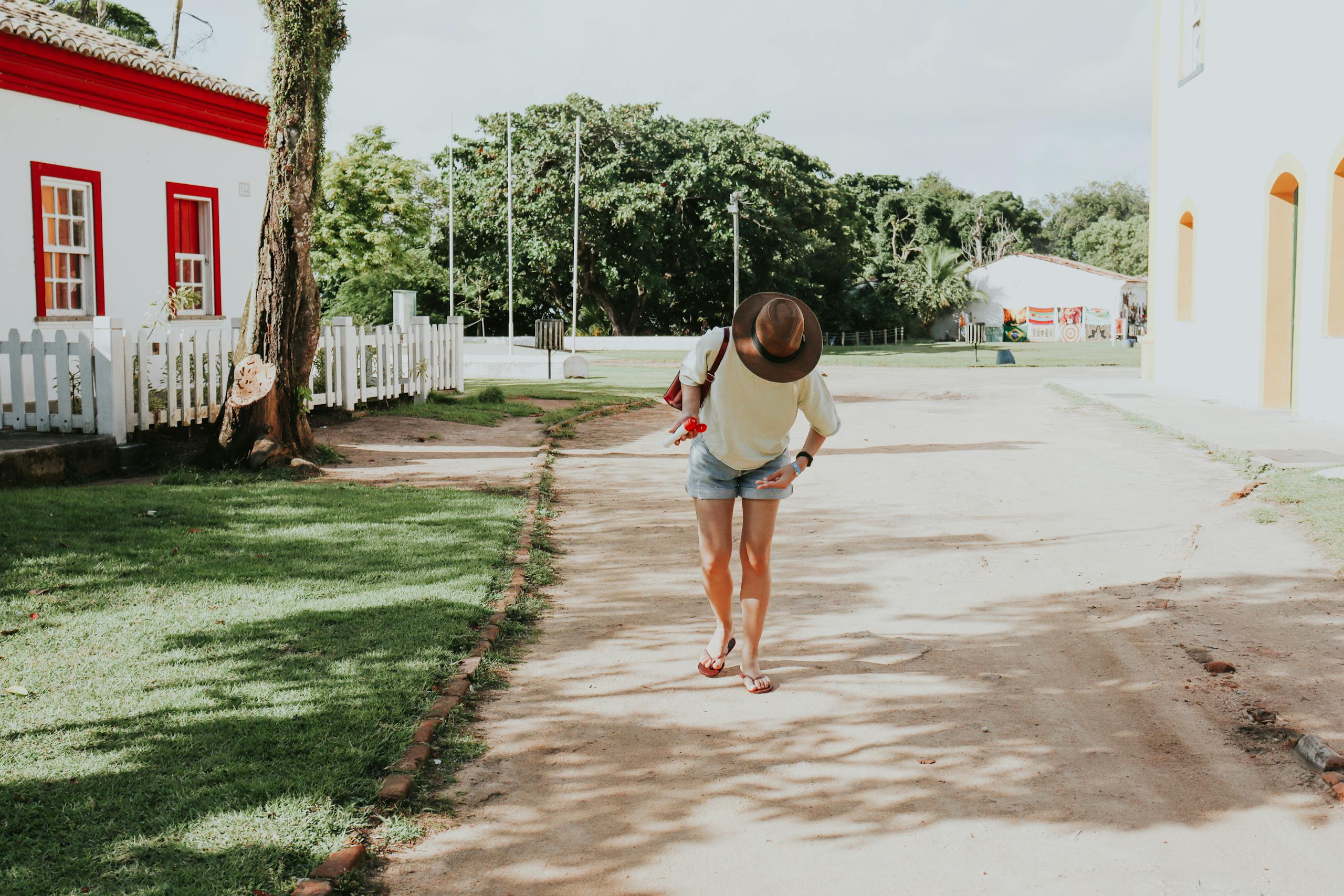 juntos seguros A woman in casual attire walks down a sunny street in Porto Seguro, Bahia, Brazil.