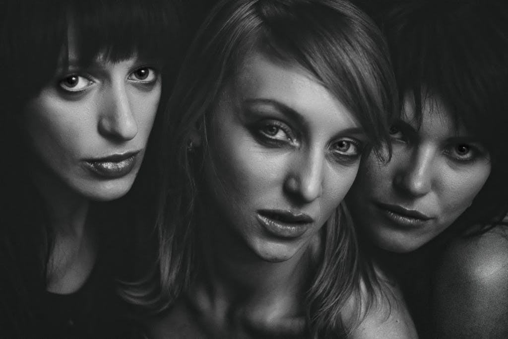 Artistic black and white portrait of three women creating a moody and intimate atmosphere.