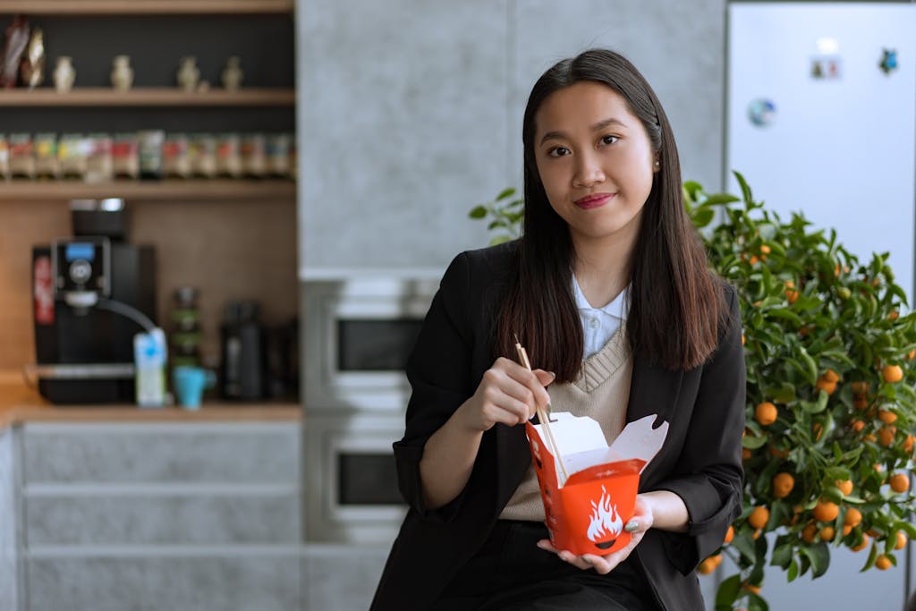 Entrepreneur Break Businesswoman enjoys a quick lunch with Asian noodles in a modern office setting.