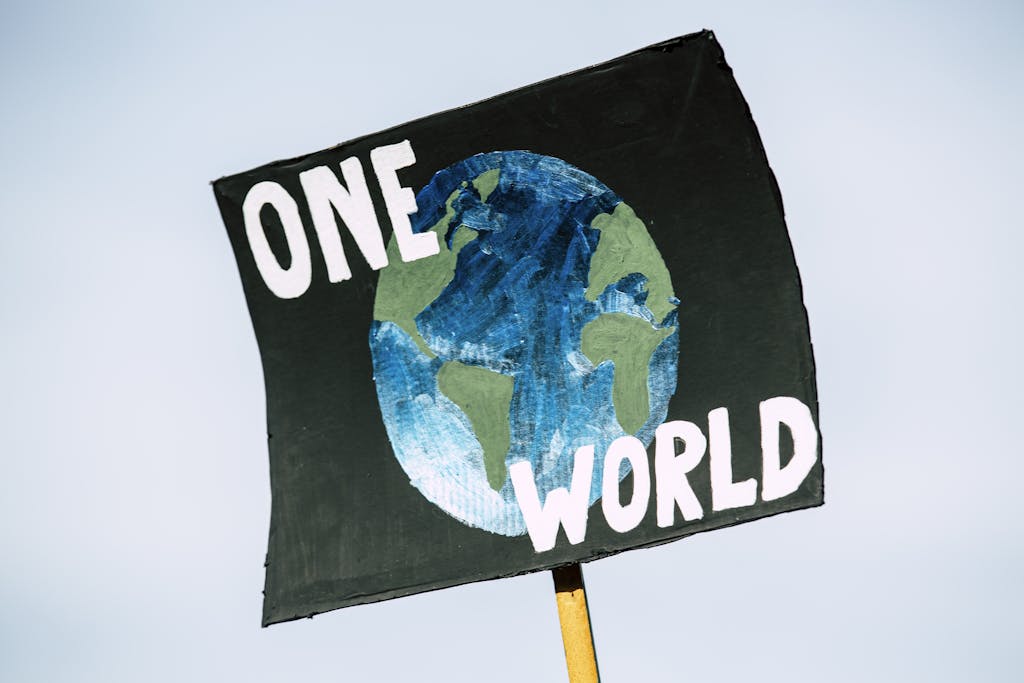 TheGlobeAndMail Close-up of a protest sign with Earth and 'One World' text, symbolizing climate change awareness.