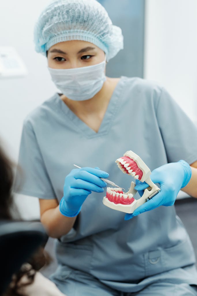 Dental Software News Today Dentist wearing scrubs using dental model to demonstrate oral hygiene techniques to a patient.