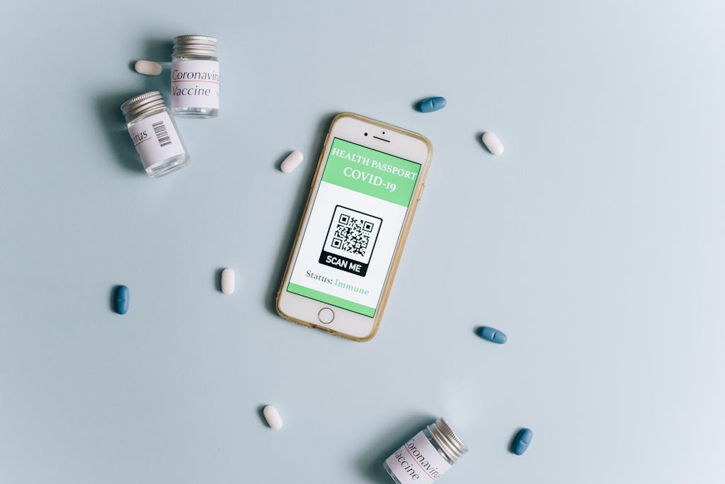 Six Sigma Certification Online Image of a smartphone displaying a health passport alongside COVID-19 vaccine vials and pills on a light blue background.