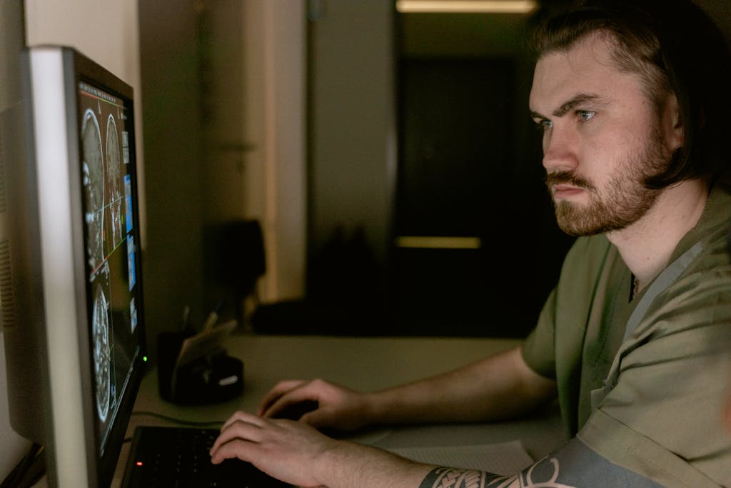 Kongotech Org Radiologist intensely studies CT scan results on computer monitor in healthcare setting.