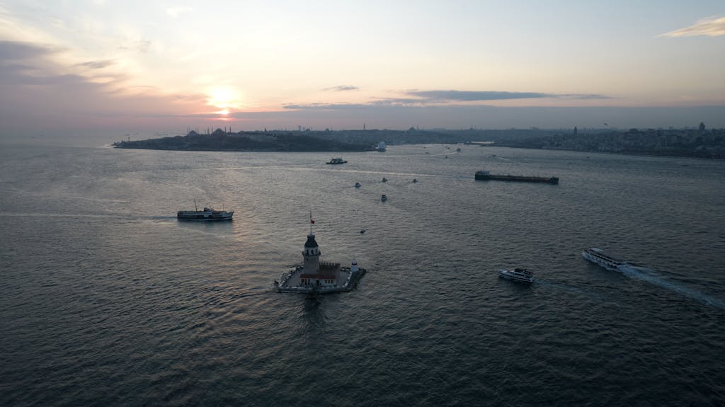 Aajkitajikhabar .com Stunning aerial view of Istanbul's Maiden's Tower at sunset with boats gliding on the Bosphorus.
