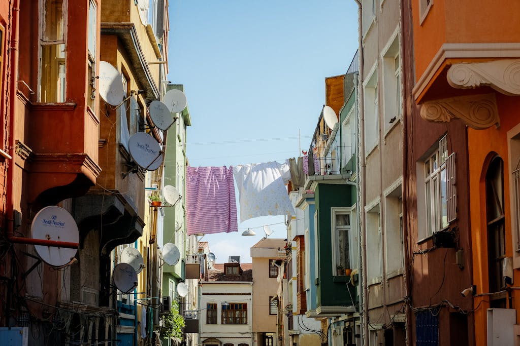 unbanned g+ Vibrant city street with laundry hanging between colorful buildings during the day.